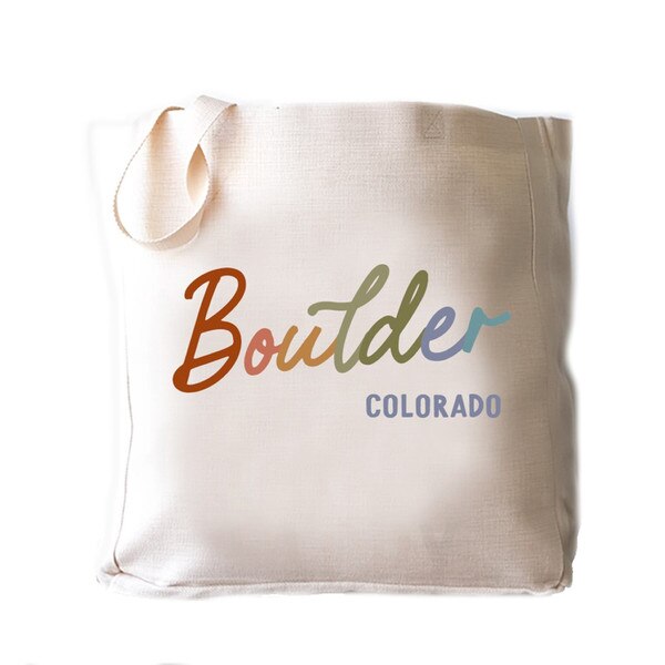 Boulder Colorado canvas tote bag with artistic multicolor text design, durable fabric, and sturdy shoulder straps.